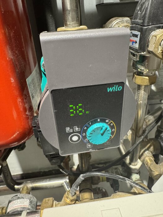Vattenpump från märket Wilo med en digital display som visar 36 W, integrerad i ett rörsystem, omgiven av ventiler och kopplingar.