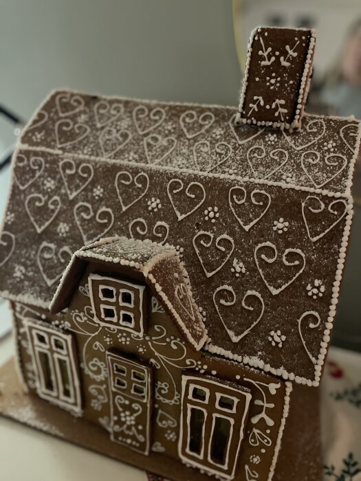 Pepparkakshus dekorerat med vita glasyrhjärtan och mönster, gjort av en 19-årig dotter som vill bo i ett liknande hus.
