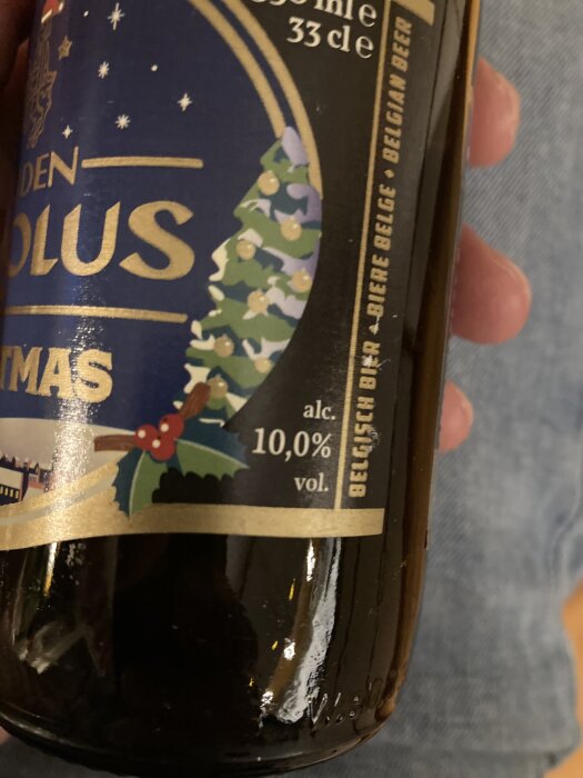 Flaska med belgisk öl, etiketten visar julmotiv och alkoholhalten 10%.