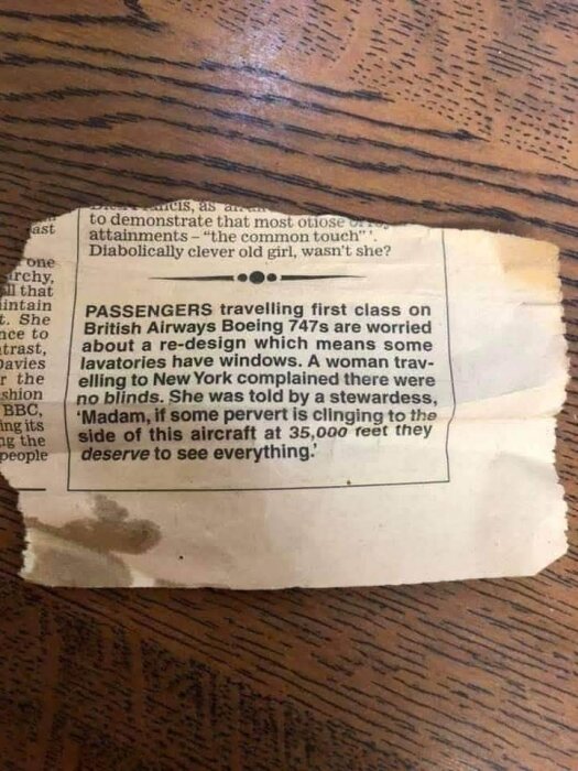 Urklipp av tidningsartikel på ett trädträbord. Text om flygpassagerare som oroar sig över designändringar på British Airways Boeing 747-flyg.