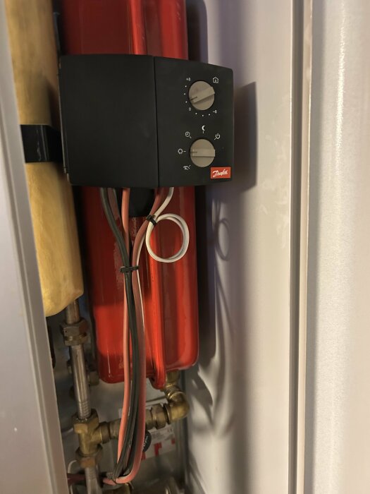 Termostatkontroll på rörsystem med röda rör och kablar.