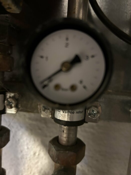 Tryckmätare på ett värmesystem, med en visning nära 1 bar, vilket kan indikera lågt tryck som påverkar radiatorernas uppvärmning.