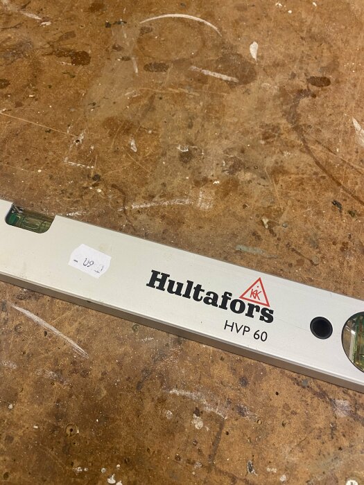 Hultafors HVP 60 vattenpass på en träbänk, prisetikett "60 kr".