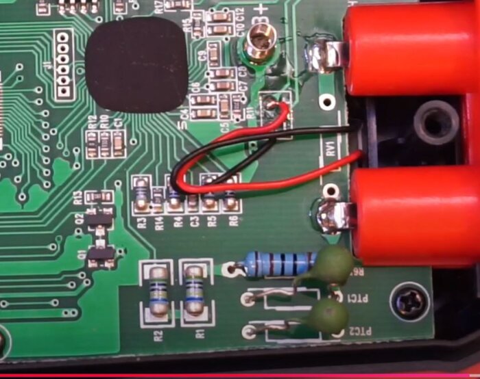 Närbild av ett kretskort med motstånd och röda kablar, relaterat till diskussion om Kaiweets och Uni-T multimeters skyddskomponenter.