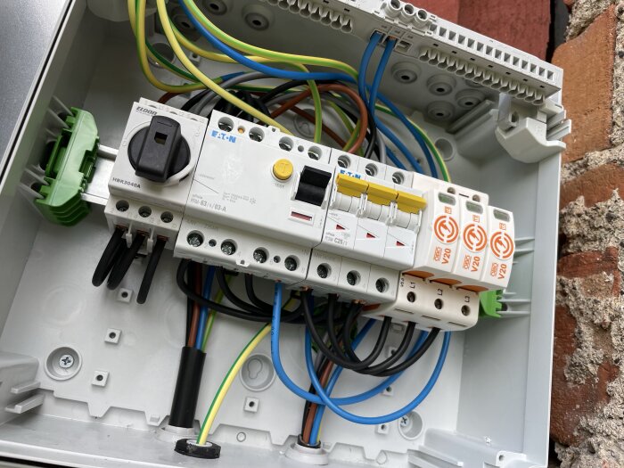 Elcentral med kablar, strömbrytare och tre gula 25A normbrytare i en byggnad med solceller och aktuell diskussion om installation av Homevolt.