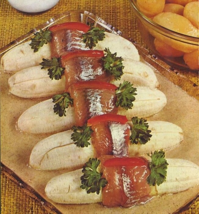 Bananas wrapped in pickled herring with parsley garnish on a platter, based on a 1963 German cookbook.