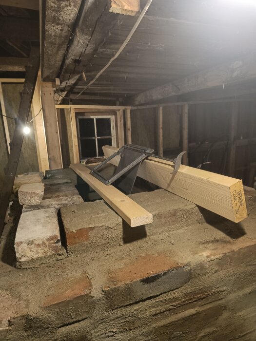 Byggarbetsplats för öppen spis under konstruktion med tegelstenar, bräda och ett omonterat vridspjäll.