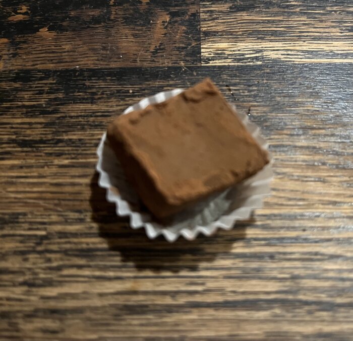 Hemgjord chokladtryffel med rostad mandel och Baileys, placerad i en vit pappersform på ett träbord.