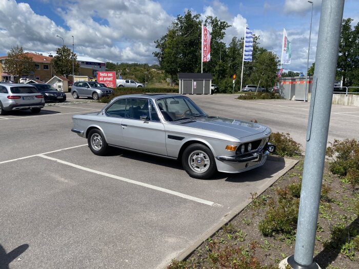 Silverfärgad klassisk bil, parkerad på en parkering i Västerås, med 80-talsfälgar, sommaren 2020.