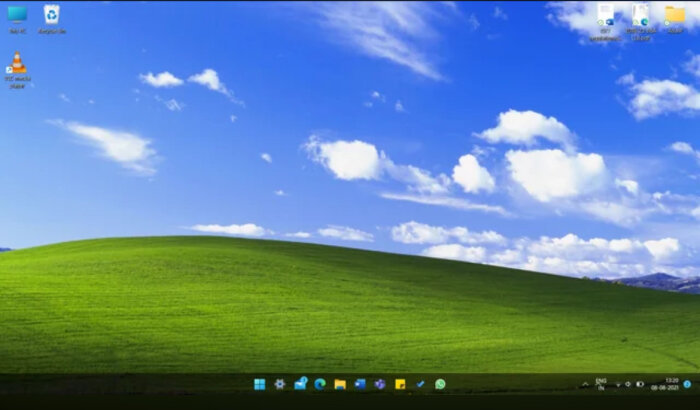 Datorskärm visar klassisk Windows XP-bakgrund med gröna kullar och blå himmel. Skrivbordsikoner och aktivitetsfält för Windows 11 syns.