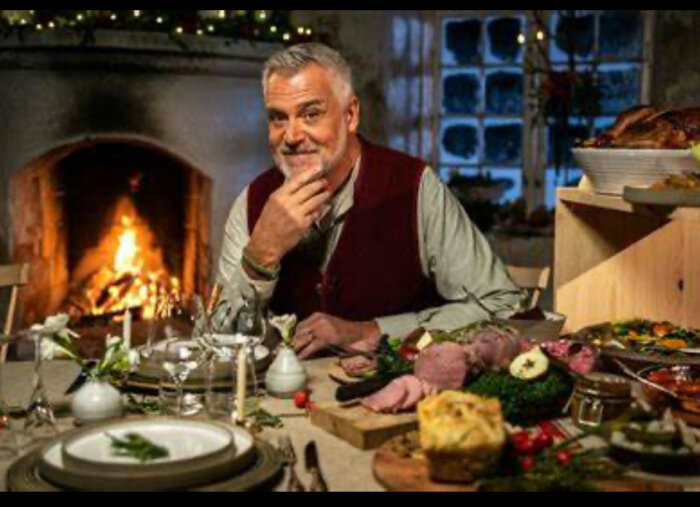 Man vid julbord framför öppen spis med dekorerad middag.
