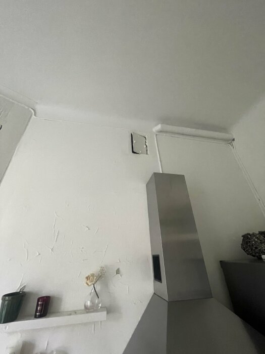 Ventilklaff ovanför köksfläkt i äldre kök under renovering med skrovlig vägg och hylla under, del av planeringsstadiet för ny köksinstallation.