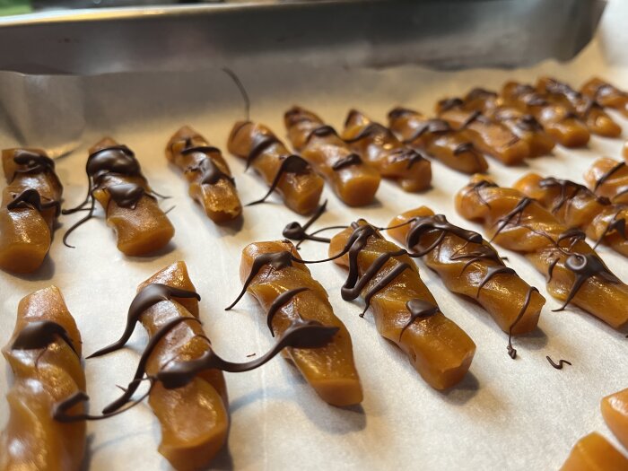 Hemlagad saffran och apelsinkola med chokladstänk på bakplåtspapper, julgodis från ett hembakat projekt, nära vy.