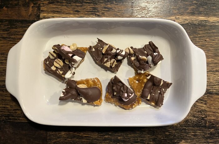 Hembakat julgodis i en vit form, bitar av jordnötskrokant och choklad med marshmallows och nötter ovanpå.