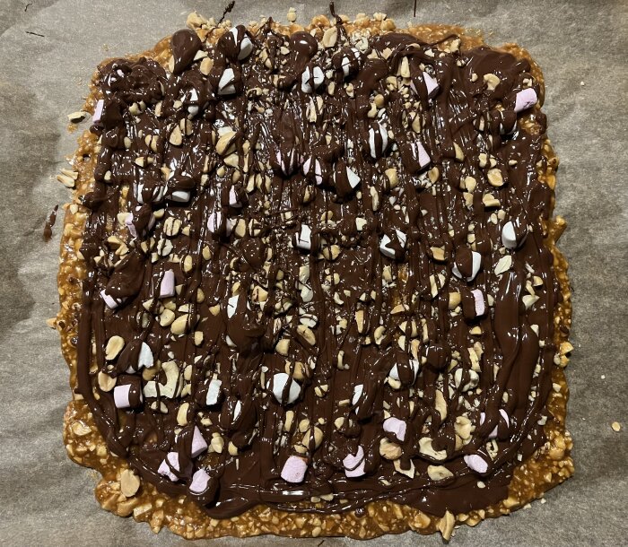 Hemlagat jordnötskrokantgodis med smält choklad och marshmallows på bakplåtspapper.