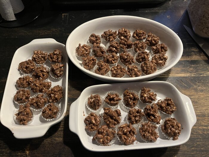 Chokladkluster med nötter och puffar i vita formar på tre vita fat, december 2024.