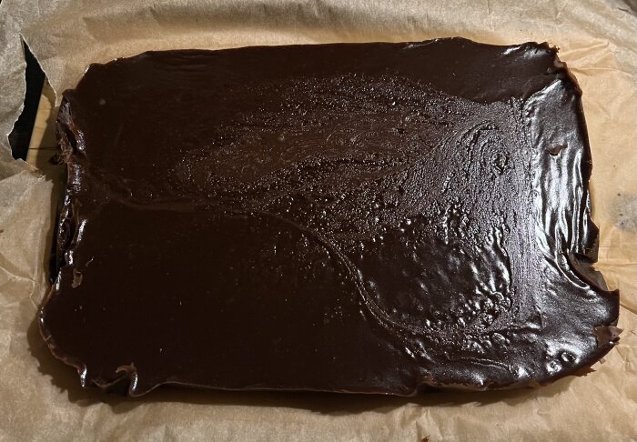 En bricka med mörk, glänsande chokladkola på bakplåtspapper.