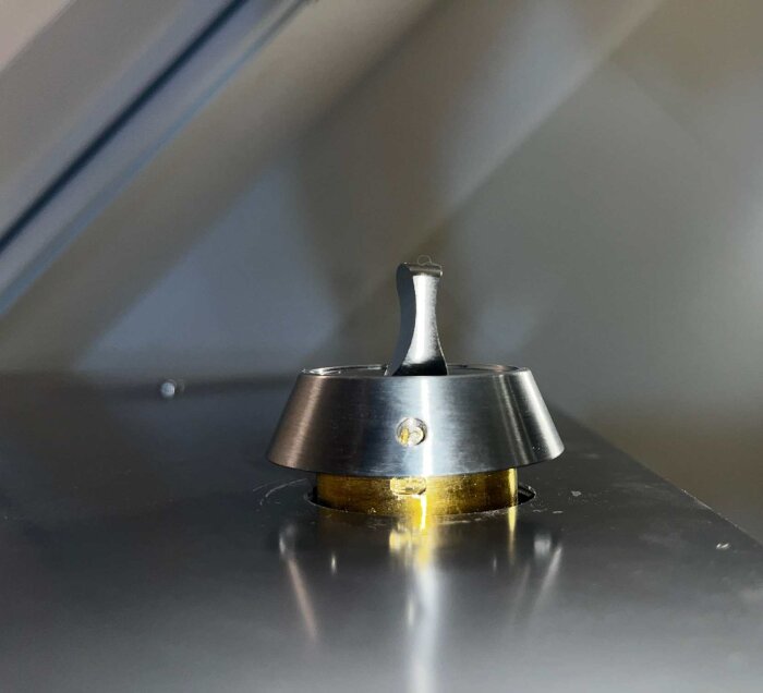 Lägenhetslås med monterad dekorhylsa och synligt vred, delvis isärtaget på en dörr.