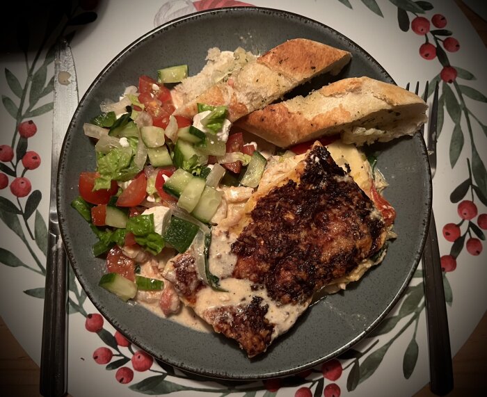 Tallrik med skaldjurslasagne, blandad sallad med gurka och tomat, samt vitlöks- och örtbröd.
