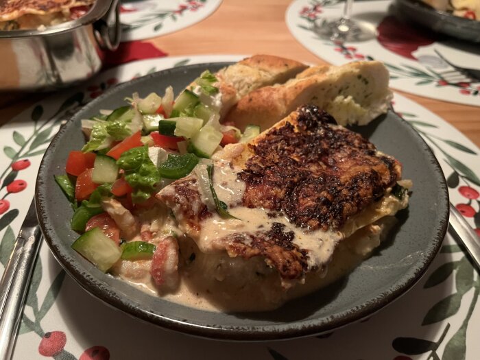Skaldjurslasagne med ricotta och tomat på tallrik, serverad med grönsallad och vitlöksbröd.