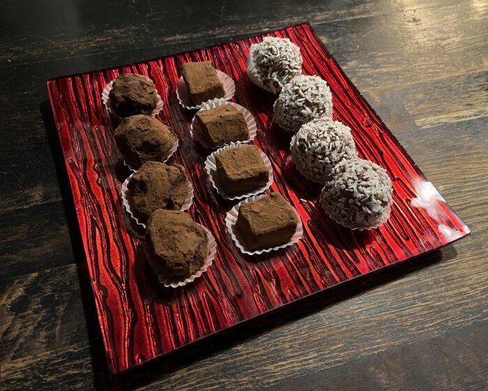 Chokladtryfflar på ett rött fat: choklad- och apelsintryfflar, baileystryfflar med rostad mandel, och kokosprydda kokodajmbollar.