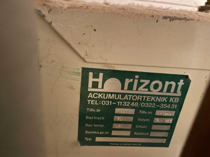 Bild av en grön produktetikett för Horizon Ackumulatorteknik KB, med tillverkningsår 1991 och kontaktuppgifter.