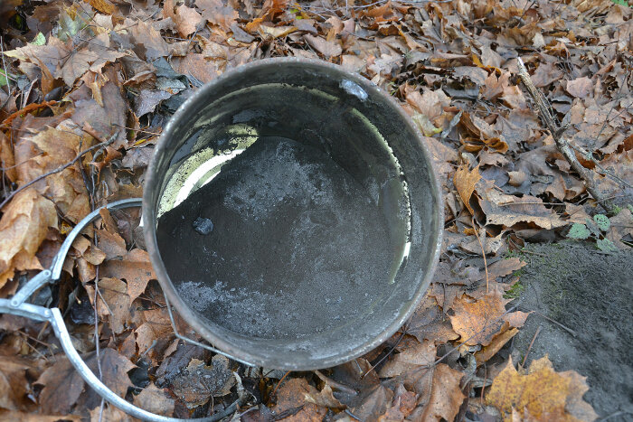 Sot från kaminen som sotats, i en metalldel liggande på marken täckt av höstlöv.