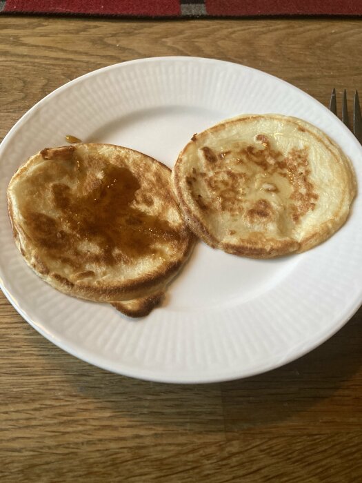 Två plättar på en vit tallrik, serverade med sirap och kanel.