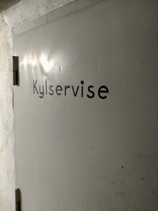 Dörr med texten "Kylservice", i ett maskinrum från 1950-talet, där endast fundamenten till gamla kylmaskiner finns kvar.