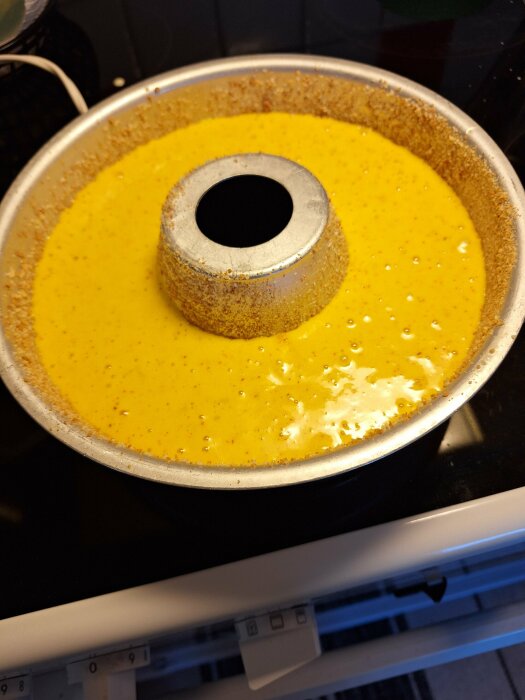 Saffranskakssmet i rund, smord och bröad bakform, redo för gräddning i ugnen.