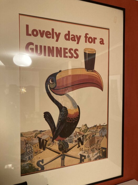 Vintage Guinness-reklamaffisch med en tukan som balanserar ett glas Guinness på näbben, texten "Lovely day for a GUINNESS" syns.