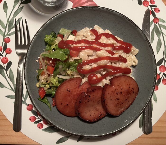 Tallrik med mjölkstuvade makaroner och stekt falukorv, toppad med ketchup, serverad med sallad.