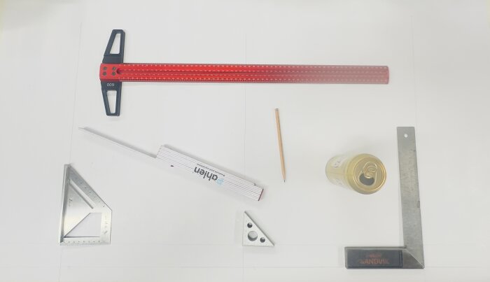 Verktyg och en ölburk placerade på ett bord: röd linjal, vinkelhake, tumstock, blyertspenna och en Sandvik märkessvinkel.