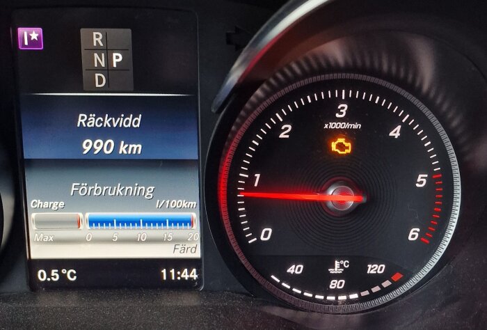 Instrumentbräda visas med motorlampan tänd och växel i parkeringsläge. Räckvidd 990 km, temperatur 0,5°C klockan 11:44.