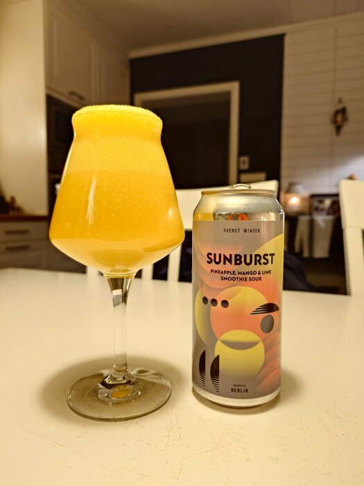 Ett glas med skummande, gul Sunburst smoothie sour från Fuerst Wiacek och dess burk på ett bord.