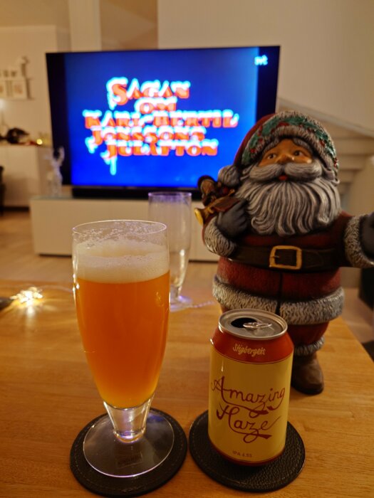 Juldekoration med tomtefigur, ölglas och burk med IPA Amazing Haze framför en tv med texten "Sagan om Karl-Bertil Jonssons Julafton".