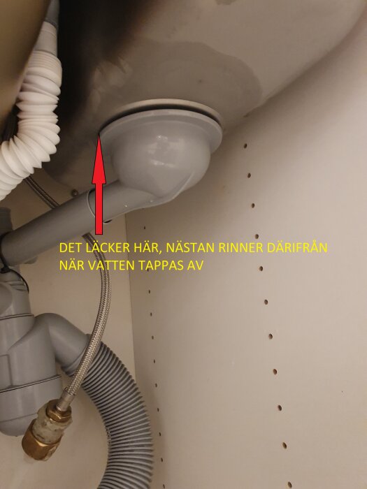 Läckage under diskhon vid anslutning av korgventilarmen, markerat med röd pil.