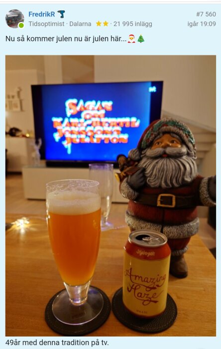 Ett glas öl och en burk öl framför en TV som visar titeln "Sagan om Karl-Bertil Jonssons julafton", bredvid står en tomtefigur på ett bord.