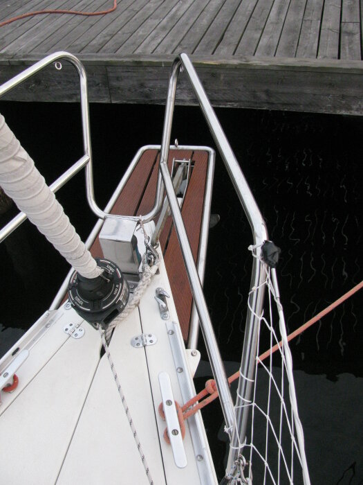 Peke på segelbåt vid brygga med reling och tågvirke.