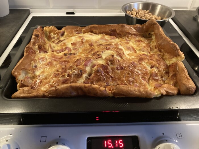 Ugnsplåt med nygräddad fläskpannkaka och skål med kanderade mandlar i bakgrunden.