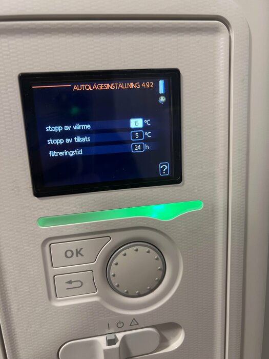 Digital display på pannstyrning med inställningar: stopp av värme 15°C, stopp av tillsats 5°C, filtreringstid 24h och grönt ljus.
