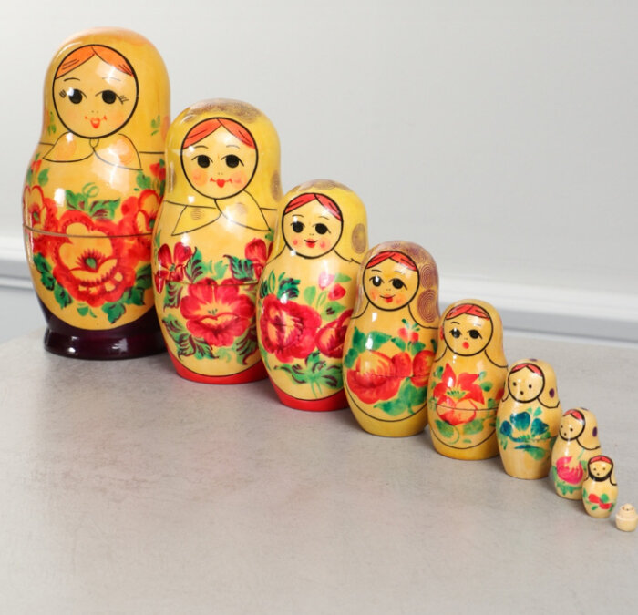 En rad med traditionella ryska matrojsjka-dockor i olika storlekar, målade i färgglada mönster, placerade på ett bord.