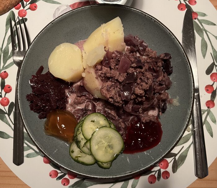 Tallrik med Kålmaja gjord på rödkål, serverad med kokt potatis, inlagd gurka, äppelgele med chili, rödkål och lingonsylt.