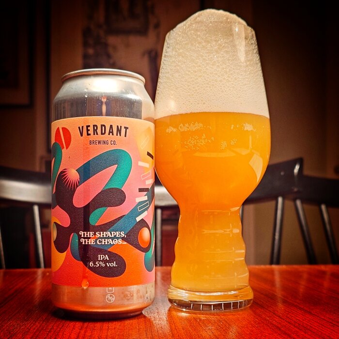 En ölburk från Verdant Brewing Co. med etiketten "The Shapes, The Chaos" bredvid ett glas med skummande öl.