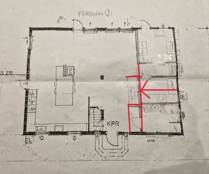 Arkitektritning med förslag på rumsfördelning. Badrum markerat i hörnet, med alternativa dörrlösningar i rött. Ytor för garderober och TV-hörna synliga.