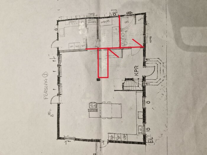 Ritning över lägenhet med badrum och tvättstuga i mitten och garderober vid ytterdörren. Röda markeringar visar möjliga förändringar i planlösningen.