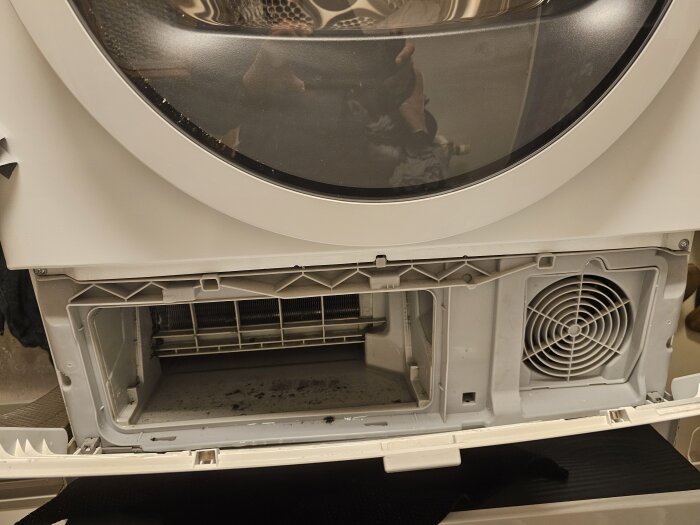 Öppen framsida av en Bosch tvättmaskin med synlig nederdel där skräp samlats. Fläkt och inre delar synliga efter rengöring.