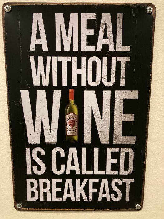 Skylt med texten "A meal without wine is called breakfast" och en illustration av en vinflaska inklusive etikett med vindruvor.