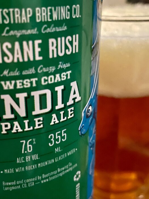 Närbild av en ölburk med etiketten "Insane Rush India Pale Ale", 7.6% alkohol, bredvid ett glas öl.