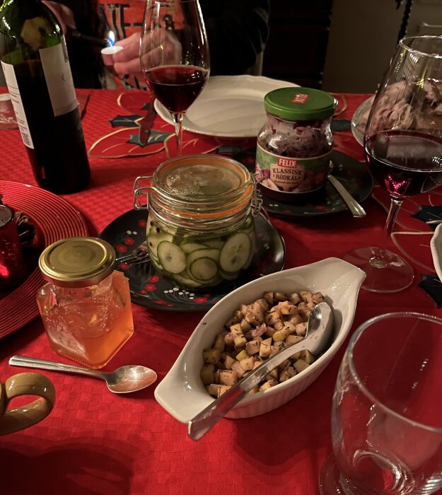 Middag med rödbetsgelé, inlagd gurka, äppelblandning och vin på röd duk.